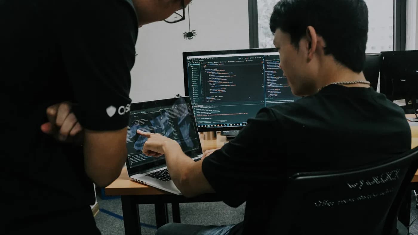 Two security engineers triaging a vulnerability finding together on a laptop
